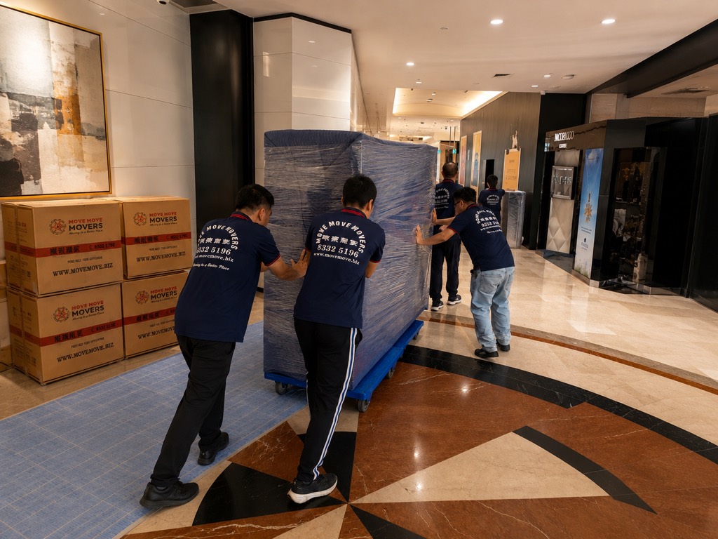 Move Move Movers crew moving wrapped furniture and cartons through a commercial lobby in Singapore