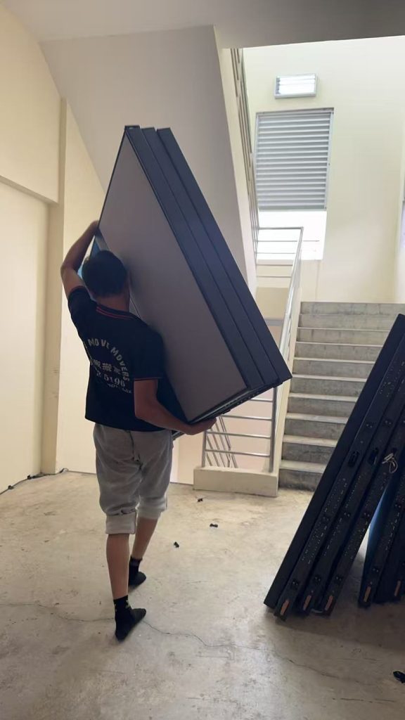 Move Move Movers crew carrying a tall partition through a Singapore staircase route