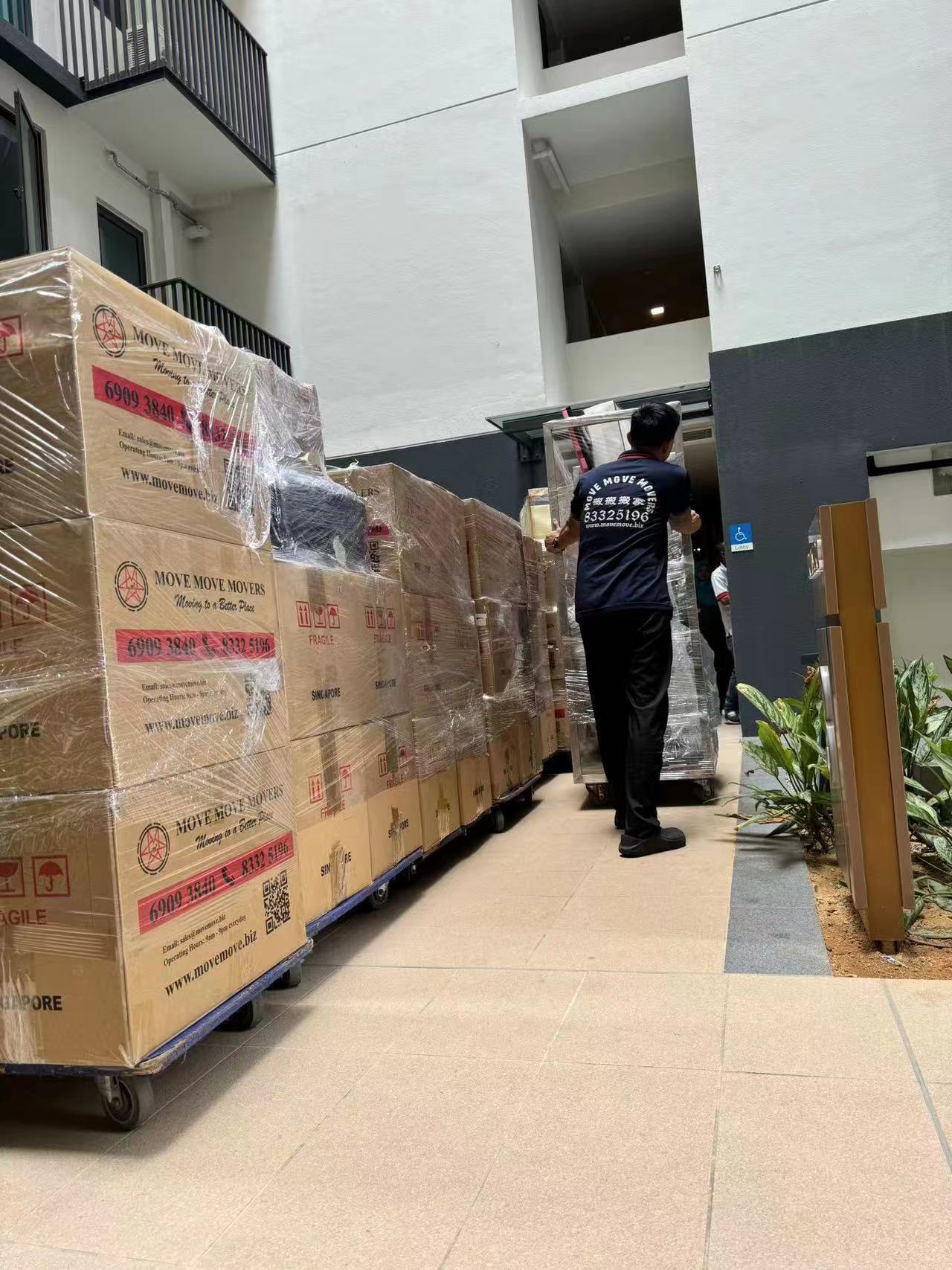 Packed cartons and wrapped furniture along condo walkway – move move movers – move move movers Move Move Movers crew walking beside packed cartons and wrapped furniture along a Singapore condo walkway